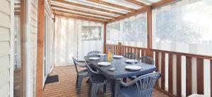 einen Tisch und Stühle auf einer Veranda mit einer Holzterrasse in der Unterkunft Naphtase MH01S Le Refuge des Pins in Saint-Jean-de-Monts