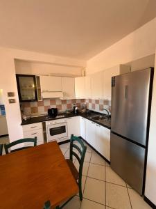 a kitchen with a table and a stainless steel refrigerator at Le Canne - Appartamento "Sole" in San Teodoro