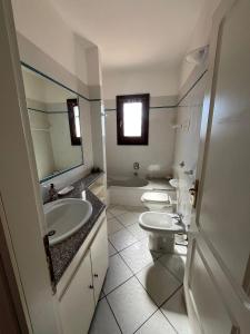 a bathroom with two sinks and a toilet and a mirror at Le Canne - Appartamento "Sole" in San Teodoro