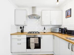 a kitchen with white cabinets and a stove top oven at 4 Bed House Port Talbot - Perfect For Contractors in Port Talbot