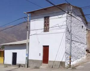a white building with a red door on a street at Caraz - Cozy Cottage in Caraz +29 photos