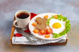 a plate with a fried egg and tomatoes and a cup of coffee at The Hotel Fairmount Plaza Near IGI Airport in New Delhi +16 photos