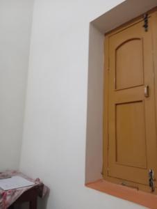 eine Tür in einem weißen Raum mit einem Tisch in der Unterkunft Aadha vatika in Deoghar
