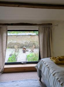 ein Schlafzimmer mit einem Fenster und einem Hund auf einer Terrasse in der Unterkunft The Roundhouse, beautiful barn in North Cornwall in North Petherwin