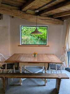 ein Esstisch mit Stühlen und ein großes Fenster in der Unterkunft The Roundhouse, beautiful barn in North Cornwall in North Petherwin