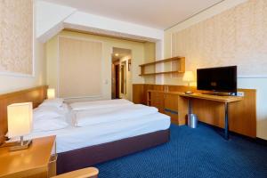 a hotel room with two beds and a flat screen tv at Hotel Strudlhof Vienna in Vienna