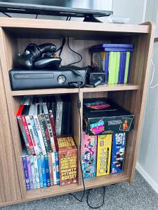 a book shelf filled with books and video games at Lovely 3 bedroom holiday home in Seton Sand caravan park Wi-Fi Xbox in Longniddry +6 photos