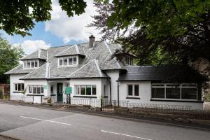 a white house on the side of a street at Glenbruar House in Crianlarich