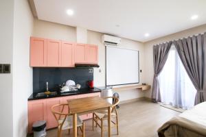 cocina con armarios rosas, mesa y sillas en SMN Homestay, en Tân Thành (1)