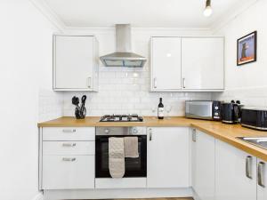 a kitchen with white cabinets and a stove top oven at 4 Bed House Port Talbot - Perfect For Contractors in Port Talbot