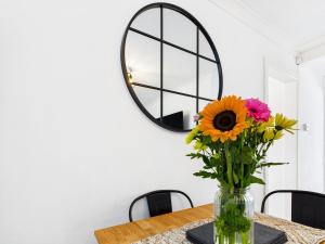 a vase of flowers on a table with a mirror at 4 Bed House Port Talbot - Perfect For Contractors in Port Talbot