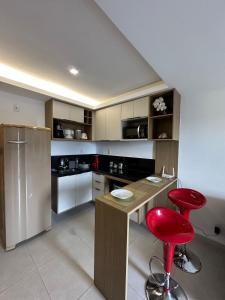 a kitchen with a wooden counter and a red stool at Apartamento lindo diamond 915 independência in Juiz de Fora