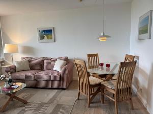una sala de estar con un sofá y una mesa en Haus Uthlande Uthlande Whg 3 Strandliebe, en Wyk auf Föhr
