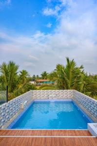 a swimming pool in a resort with palm trees at hotel beachfront in Calangute