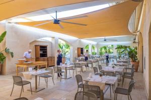 a restaurant with tables and chairs and people in the background at Vivosa Apulia Resort in Ugento