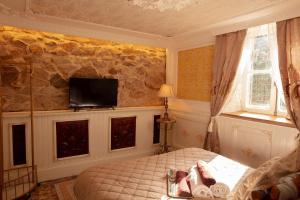 a bedroom with a bed and a tv on a stone wall at Au Petit Chateau les Bains in Morvan in Saint-Honoré-les-Bains