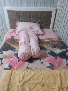 a bed with pink flowers and pillows on it at Kanaya house in Jakarta