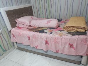 a small bed with a pink blanket and pillows on it at Kanaya house in Jakarta