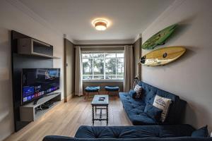 un soggiorno con divano e tavola da surf sul muro di SHB - Pé na Areia em Santos: Sol, Mar e Netflix a Santos