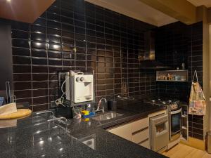 una cucina con piastrelle nere sul muro e un lavandino di SHB - Pé na Areia em Santos: Sol, Mar e Netflix a Santos Altre 66 foto