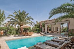 a swimming pool with chairs and a house at Villa AIMA - avec Gourvernante in Douar Soukkane