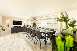 een eetkamer met een lange tafel en stoelen bij Villa Santa Rosa by Algarve Vacation in Armação de Pêra