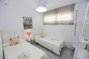 Una habitación blanca con dos camas y una ventana. en Alcazaba Del Mar parking next to the beach, en La Herradura