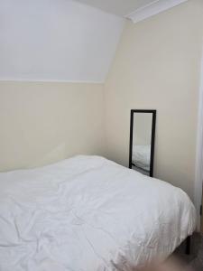 Un dormitorio con una cama blanca y un espejo. en Colchester Comfortable room Oo, en Hythe