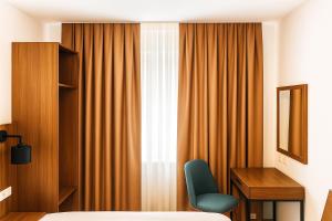 ein Schlafzimmer mit Bett, Schreibtisch und Fenster in der Unterkunft Lillys Hotel München in Unterschleißheim