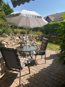 een tafel en twee stoelen met een paraplu bij geschmackvoll eingerichtete Wohnung in mediterranem Flair in Sponheim