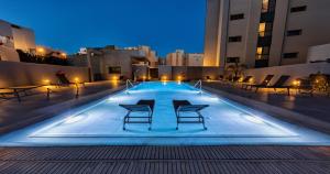 a swimming pool with chairs and lights in a building at Vértice Indalo Almería in Almería