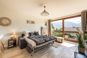a bedroom with a bed and a large window at Studio Aurore - Charmant logement avec vue montagnes in Sévrier