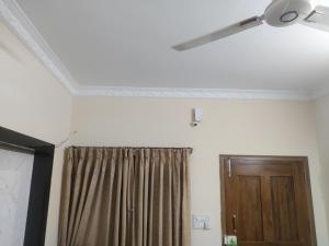 a room with a ceiling fan and a curtain and a door at Zenobia House in Udupi