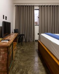 une chambre avec un lit et un bureau avec une télévision dans l'établissement Nana Suites, à Foz do Iguaçu