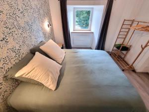a bedroom with a bed with pillows and a window at L'Ecole Buissonnière de Mazalibrand in Bronac
