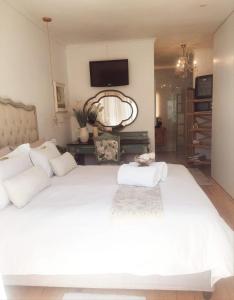 a bedroom with a large white bed with a tv on the wall at LaPlace in Strand +4 photos