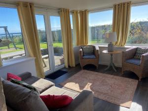a living room with a couch and chairs and large windows at Meggie Allans in Crail