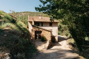 a small stone house on a hill with a road at El Molí Nou - Rural flats in Peñarroya de Tastavins