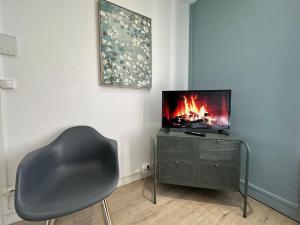 a chair sitting in a room with a television at C Oslo - Appartement spacieux proche centre-ville in Charleville-Mézières
