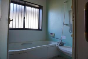 een badkamer met een bad, een wastafel en een raam bij 和風グランピング LYS AIBA House 一 わんちゃんと泊まれる一棟貸古民家一Japanese Style Glamping Dog Friendly Private Villa in Takashima +16 foto's