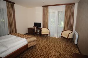 a hotel room with a bed and a desk and chairs at Hotel Balkana Vidović in Mrkonjić Grad