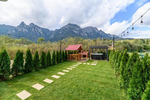 a garden with a gazebo and mountains in the background at Ama Garden Spa Apartment Busteni in Buşteni