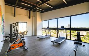 a gym with three treadmills and cardio equipment in a room with windows at Departamento de lujo en zona Carmelitas in Asuncion