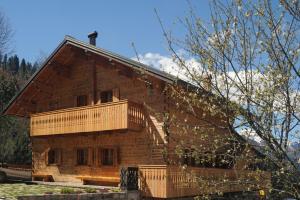 a log house with a balcony on the side of it at Dolomiti Village in Comeglians