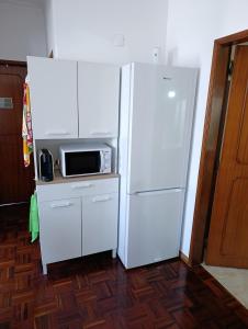 Elle comprend un réfrigérateur blanc et un four micro-ondes. dans l'établissement Casa da Familia Pereira, à Corroios