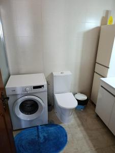 une petite salle de bains avec un lave-linge et des toilettes. dans l'établissement Casa da Familia Pereira, à Corroios 1 autre photo