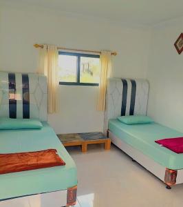 a room with two beds and a window at Penginapan JANNAH Syariah in Takengon
