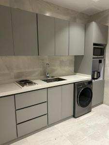 eine Küche mit weißen Schränken und einer Waschmaschine in der Unterkunft Two Bedroom Luxury Apartment in Dschidda