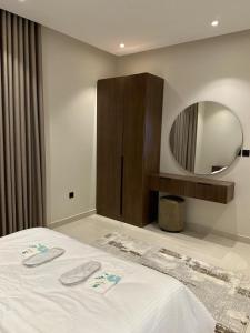 Schlafzimmer mit einem weißen Bett und einem Spiegel in der Unterkunft Two Bedroom Luxury Apartment in Dschidda