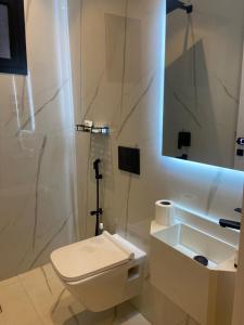 ein Badezimmer mit Toilette, Waschbecken und Spiegel in der Unterkunft Two Bedroom Luxury Apartment in Dschidda + 7 Fotos
